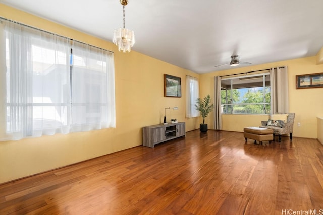 unfurnished room featuring ceiling fan with notable chandelier and wood-type flooring