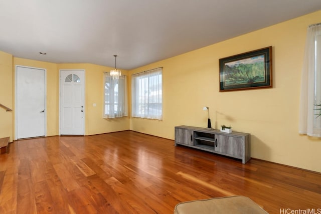 unfurnished living room with wood-type flooring and a notable chandelier