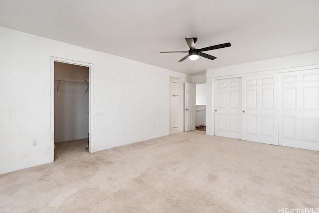 unfurnished bedroom with light carpet, ceiling fan, and a spacious closet