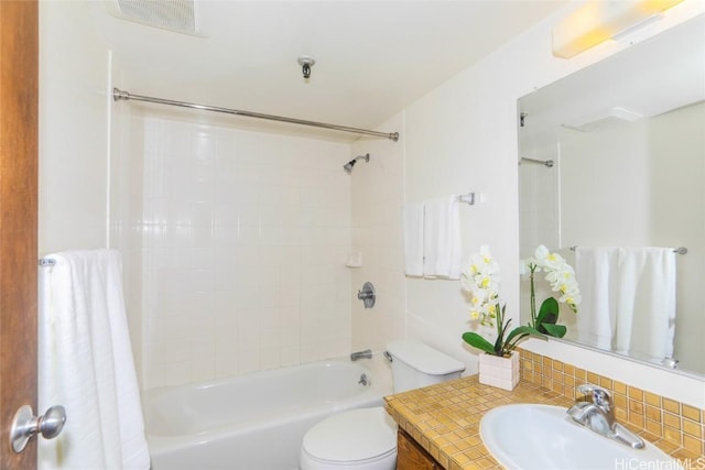 full bathroom with tiled shower / bath, vanity, and toilet