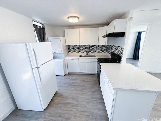 kitchen with a center island, sink, white appliances, white cabinetry, and stacked washer / dryer