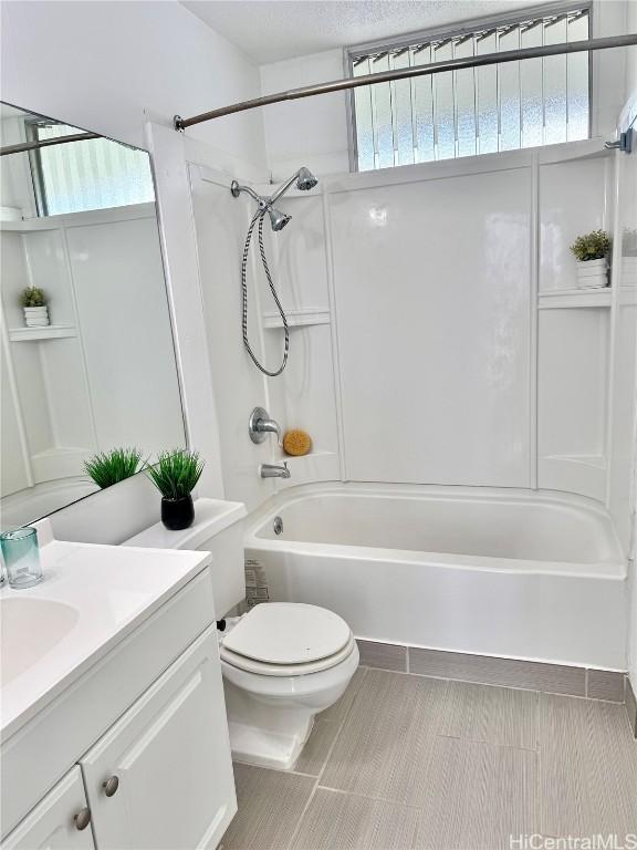 full bathroom featuring washtub / shower combination, vanity, toilet, and a textured ceiling