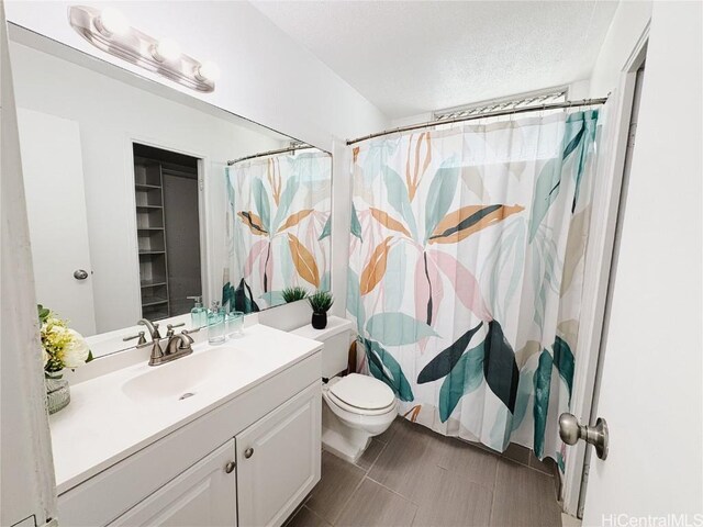 bathroom with vanity, a textured ceiling, toilet, and walk in shower