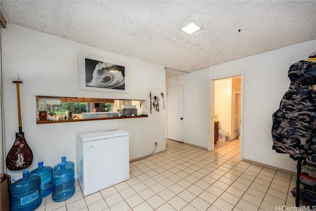 laundry room featuring light tile patterned floors and a textured ceiling