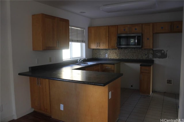 kitchen with decorative backsplash, tile patterned floors, kitchen peninsula, and sink