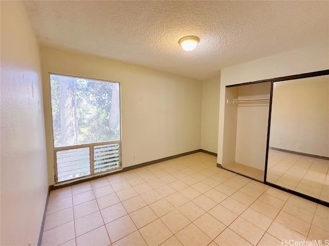 unfurnished bedroom with a textured ceiling, a closet, and light tile patterned flooring