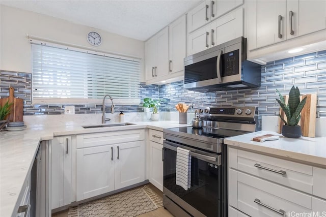 kitchen featuring tasteful backsplash, white cabinets, sink, and stainless steel appliances