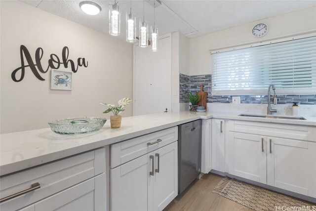 kitchen with decorative light fixtures, stainless steel dishwasher, sink, light wood-type flooring, and white cabinets