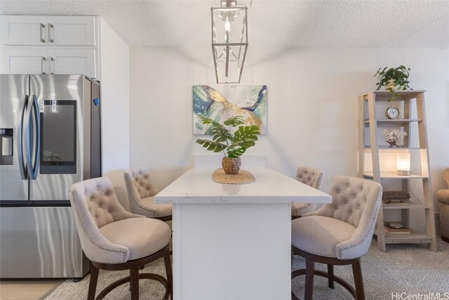 dining space with light carpet and a textured ceiling