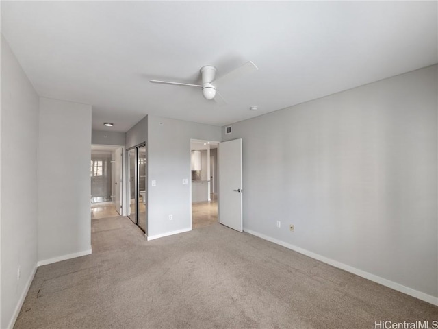 unfurnished bedroom with light colored carpet, connected bathroom, and ceiling fan