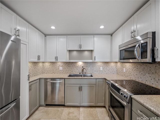 kitchen featuring sink, decorative backsplash, light stone countertops, and stainless steel appliances