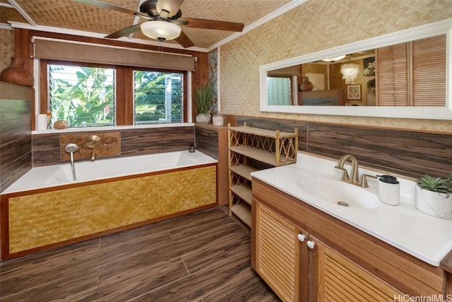 bathroom featuring tiled bath, vanity, crown molding, and ceiling fan