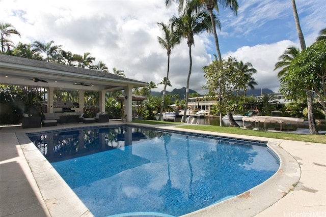 view of swimming pool featuring a patio, a water view, an outdoor hangout area, and ceiling fan