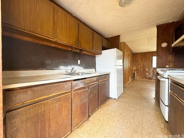 kitchen featuring sink, white appliances, and wood walls