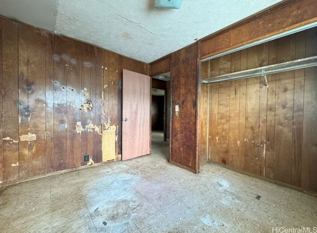 unfurnished bedroom featuring a textured ceiling and wooden walls