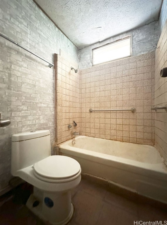 bathroom with tile patterned floors, a textured ceiling, toilet, and tiled shower / bath combo