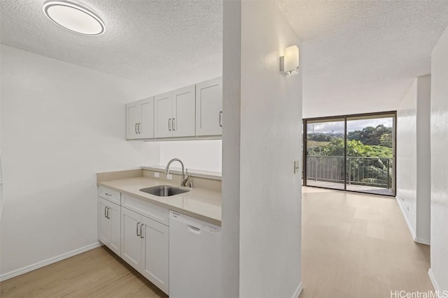 kitchen featuring white dishwasher, light hardwood / wood-style floors, white cabinets, and sink