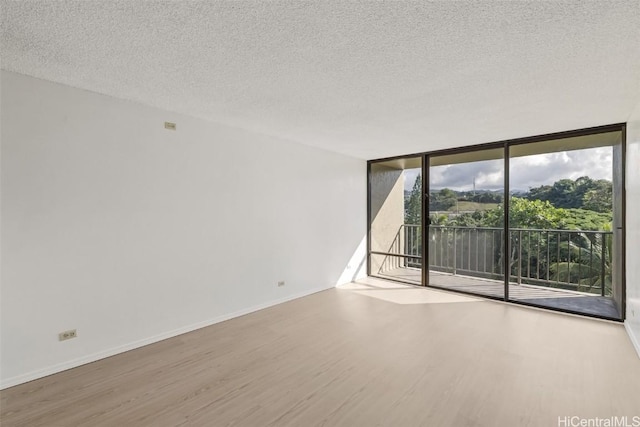 unfurnished room featuring floor to ceiling windows, hardwood / wood-style floors, and a textured ceiling