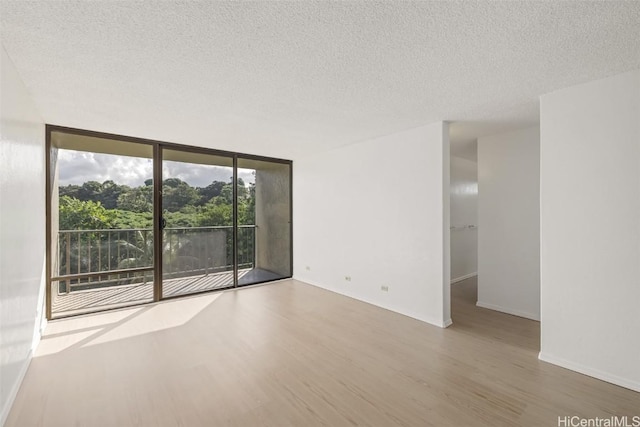 unfurnished room with a wall of windows, a textured ceiling, and hardwood / wood-style flooring