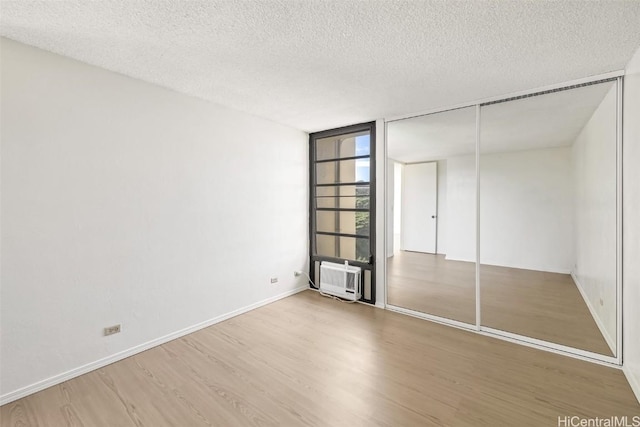 unfurnished bedroom featuring a textured ceiling, a wall of windows, a closet, and hardwood / wood-style floors