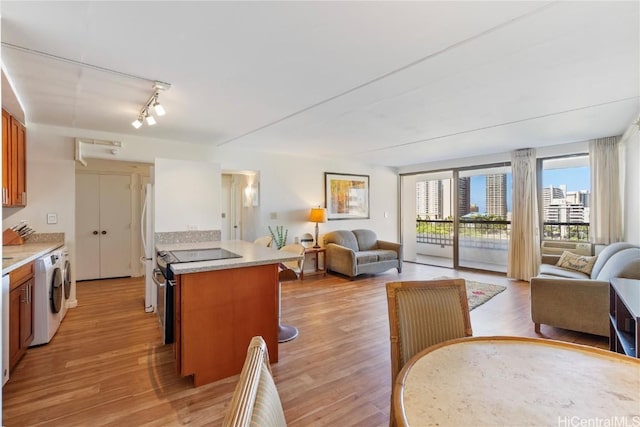 interior space featuring washer / dryer, kitchen peninsula, electric range, light hardwood / wood-style flooring, and white refrigerator