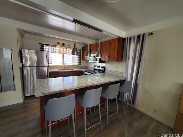 kitchen featuring stainless steel appliances, decorative light fixtures, kitchen peninsula, and sink