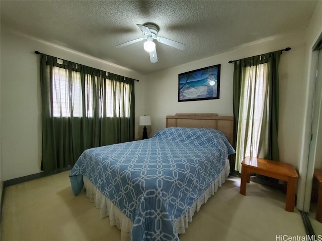 carpeted bedroom featuring ceiling fan and a textured ceiling