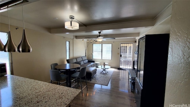 dining space with wood finished floors, beamed ceiling, and a ceiling fan