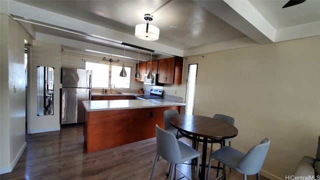 kitchen with a sink, dark wood-style floors, stainless steel appliances, a peninsula, and hanging light fixtures