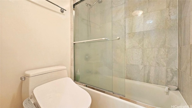 bathroom featuring toilet and combined bath / shower with glass door