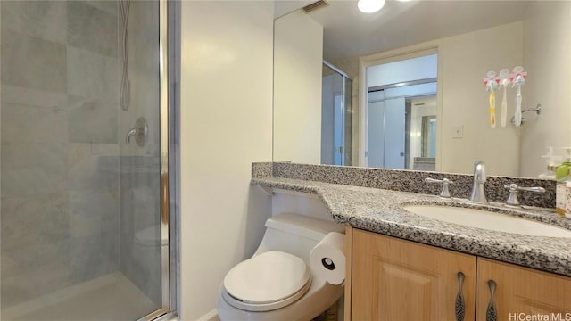 bathroom with a shower with door, vanity, and toilet