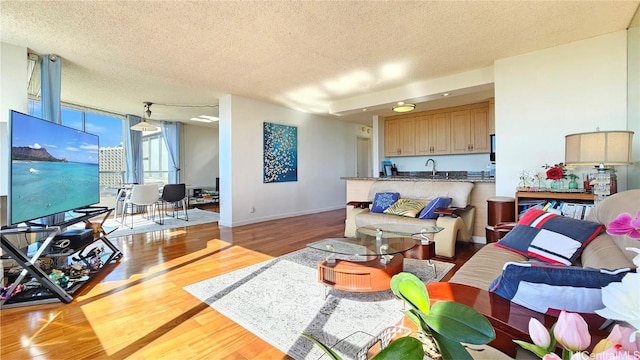 living room with sink, light hardwood / wood-style floors, and a textured ceiling