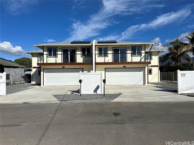 view of front of property featuring a garage, a balcony, and solar panels