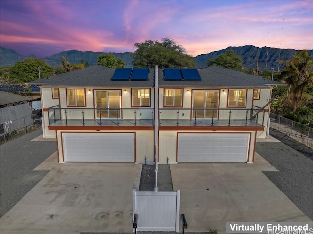 view of front of house with a garage, a mountain view, and solar panels