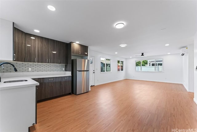 kitchen featuring sink, dark brown cabinets, stainless steel fridge, and a wall mounted AC