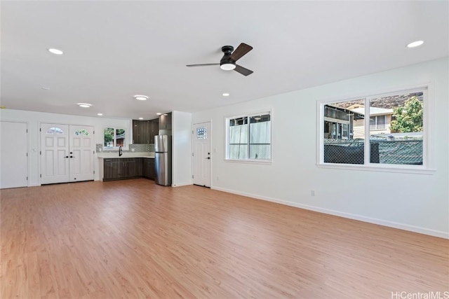 unfurnished living room with sink, ceiling fan, and light hardwood / wood-style flooring