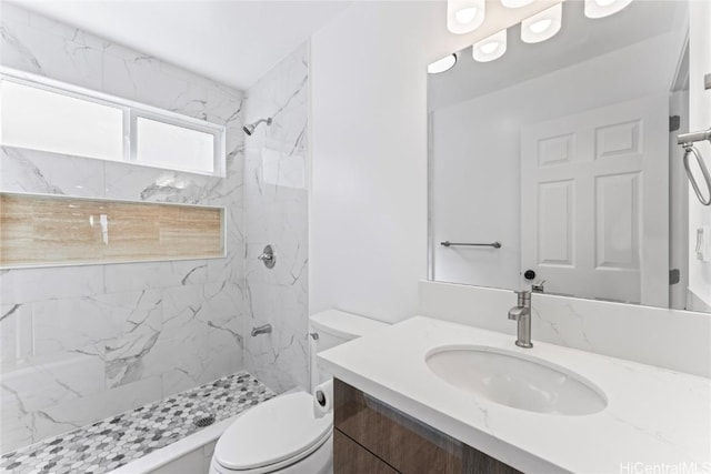 bathroom with tiled shower, vanity, and toilet