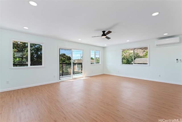 unfurnished room with a wall mounted air conditioner, light hardwood / wood-style floors, and ceiling fan