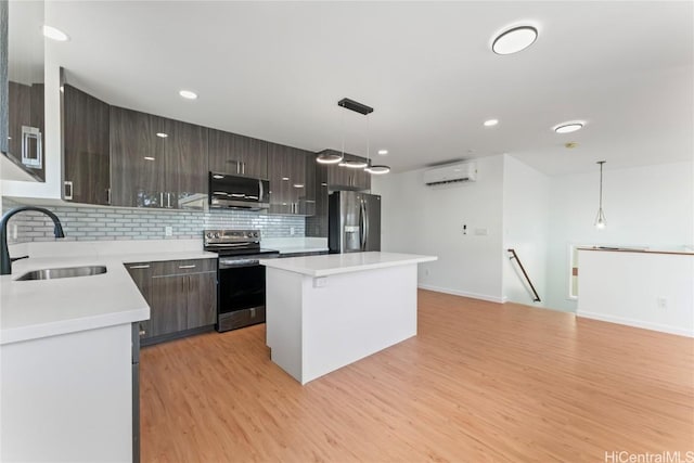 kitchen featuring sink, a wall mounted AC, a center island, hanging light fixtures, and appliances with stainless steel finishes