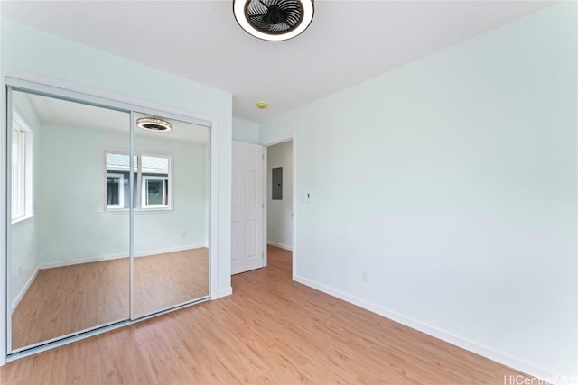 unfurnished bedroom with a closet, electric panel, and light hardwood / wood-style flooring