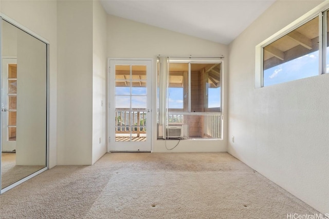 empty room featuring cooling unit, vaulted ceiling, and light colored carpet