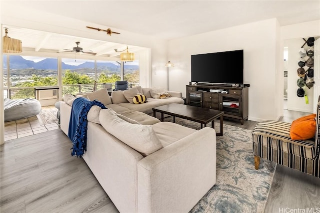 living room featuring ceiling fan, beamed ceiling, and wood-type flooring