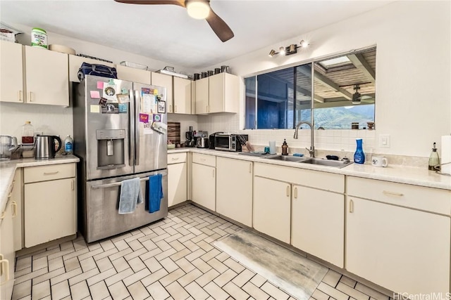 kitchen featuring sink, cream cabinets, ceiling fan, and stainless steel fridge