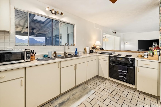 kitchen featuring ceiling fan, sink, kitchen peninsula, backsplash, and range with electric stovetop