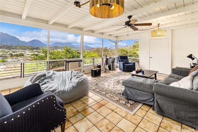 sunroom with a mountain view, ceiling fan, and beam ceiling