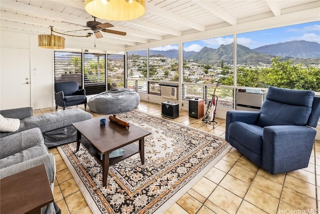 sunroom / solarium featuring a mountain view, beamed ceiling, and ceiling fan