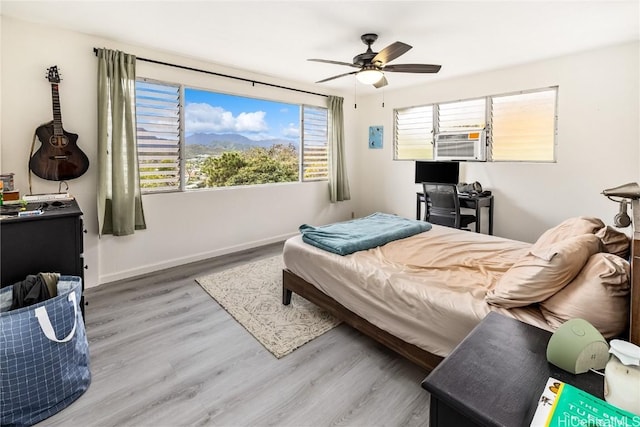 bedroom featuring light hardwood / wood-style floors, cooling unit, and ceiling fan