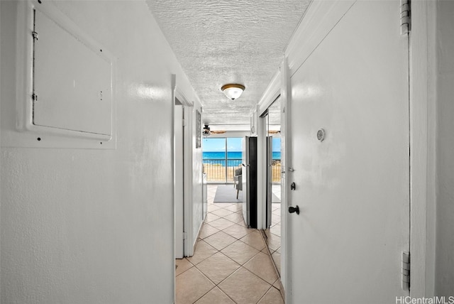 corridor featuring light tile patterned floors, a textured ceiling, and electric panel