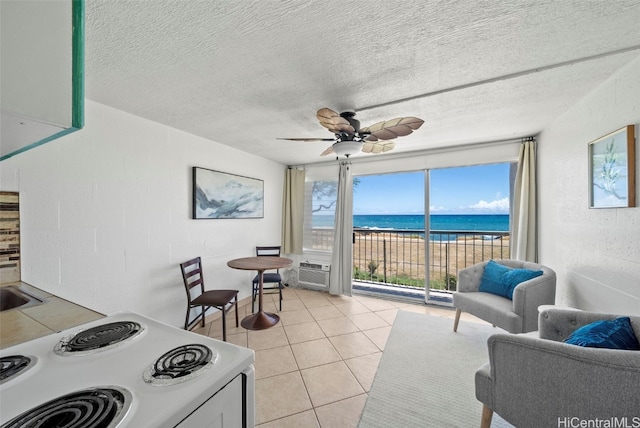 living room featuring a water view, light tile patterned floors, ceiling fan, and a textured ceiling