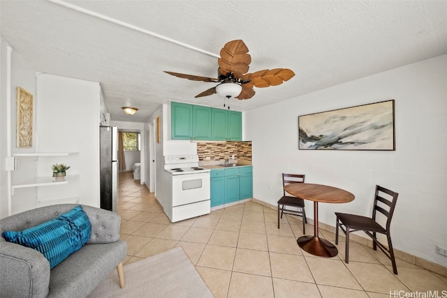 kitchen featuring tasteful backsplash, sink, white electric stove, light tile patterned floors, and stainless steel fridge